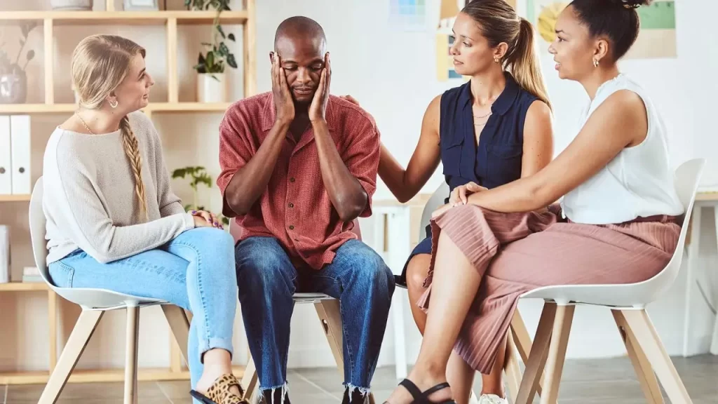 Grupo de pessoas apoiando um homem preocupado